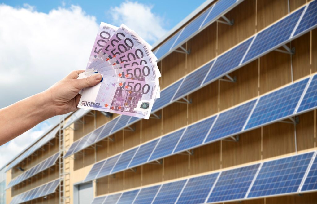 duurzaam zonnepanelen huren wordt gesymboliseerd door hand die geld vasthoudt langs een dak met zonnepanelen.