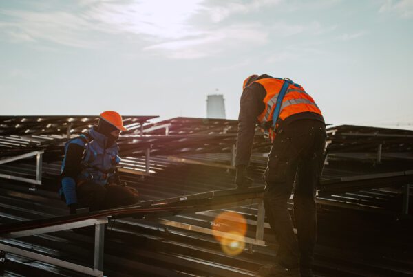 Techniekers op een dak tijdens een installatie van zonnepanelen.