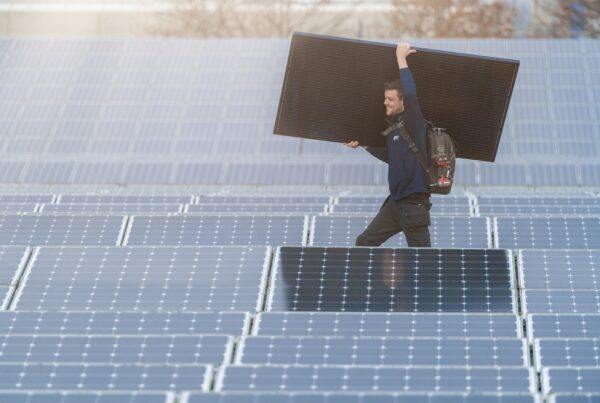 Technieker draagt zonnepaneel op dak bezaaid met zonnepanelen, voordeel door installatie Futech
